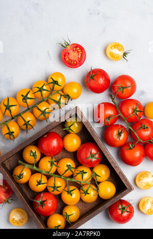 Assortiment de tomates sur la table rustique, dans un coffret en bois rouge jaune ensemble et couper, vue du dessus Banque D'Images