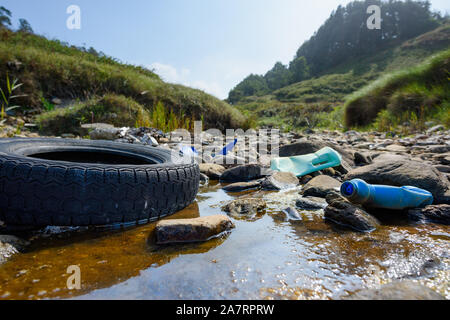 La pollution de l'environnement mondial des plastiques de la terre d'urgence. Vieille voiture tire dans l'eau sale avec des bouteilles en plastique et corbeille. Banque D'Images