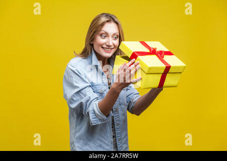 Présent tant attendu. Curieux Portrait de femme en chemise en jean à l'intérieur de boîte-cadeau, contrôler ce qui est à l'intérieur, unboxing avec satisfait heureux expressi Banque D'Images