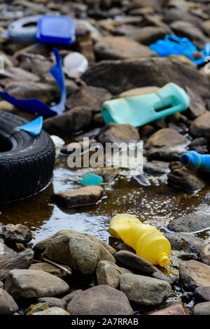 La pollution par les ordures des déchets en plastique dans l'eau huileuse, sale sur la rive de l'océan Banque D'Images