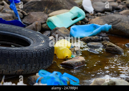 La pollution de l'environnement. Avec des pneus en caoutchouc, les déchets en plastique dans l'eau sale. Banque D'Images