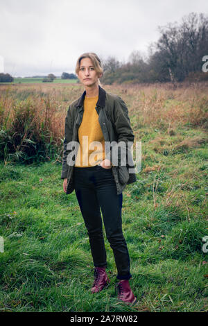 Portrait of a blond woman standing in field avec la main dans sa poche Banque D'Images