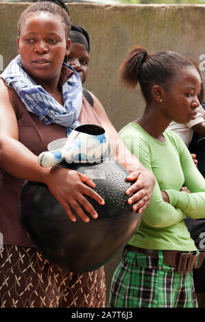 Une femme portant un pot de bière zoulou noir contenant de la bière au marula Marula Tembe festival dans le KwaZulu-Natal, Afrique du Sud. Banque D'Images