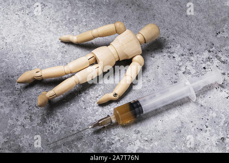 Sur le concept d'abandon. Une seringue à médicaments et à côté se trouve une figure d'un homme de d'arbre. Danger mortel Banque D'Images