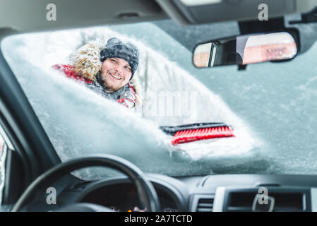 Voiture de nettoyage après la tempête de neige smiling man with brush Banque D'Images