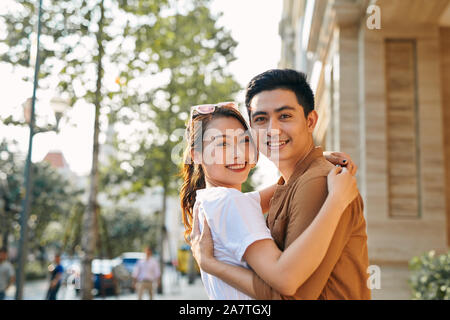 Vue arrière d'un jeune couple hugging dans une ville de destination tout en se tenant dans le quartier commerçant à proximité d'un magasin de chaussures de qualité de luxe, à l'extérieur Banque D'Images