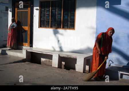 Deux femmes indiennes sont balayant le sol à l'extérieur de leur maison à Udaipur, Inde Banque D'Images