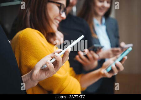 Groupe de jeunes gens positifs attendre en ligne avec smartphone moderne. L'équipe d'adultes à l'aide de mains téléphone. Réunion Concept Banque D'Images