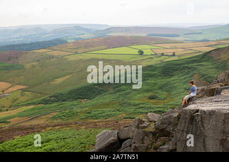 Un jeune garçon à la recherche d'un bout à l'avis du Peak District. Banque D'Images