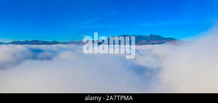 Vol au-dessus des nuages, brouillard lever du soleil paysage de montagne avec les nuages bas Banque D'Images