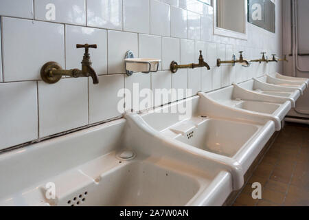 Rangée de lavabos blancs sales / lavabos dans la salle de bains d'une clinique désaffectée Banque D'Images