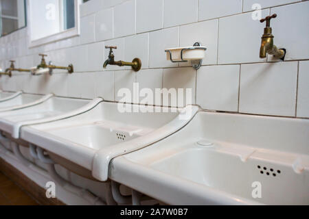 Rangée de lavabos blancs sales / lavabos dans la salle de bains d'une clinique désaffectée Banque D'Images