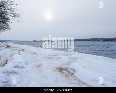 Ligne de côte Lielupe debouchment à mer Baltique après tempête avec des arbres tombés durant le gel de l'hiver avec des tons gris et ciel nuageux Banque D'Images
