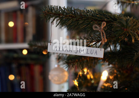 Ornements de Noël suspendu à une branche d'arbre de Noël. Beaux ornements en bois blanc dit 'Merry Christmas' en finnois. Il y a aussi des sphères. Banque D'Images