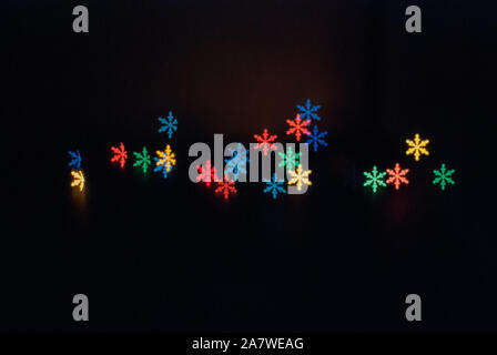 Belle abstract pattern avec flocon colorés sur fond noir. L'élément de décoration de Noël. Maison de vacances saisonnières effet glow light Banque D'Images