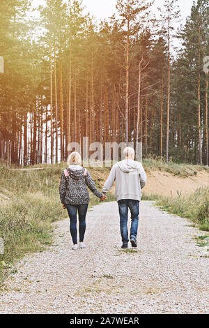 Couple de baby-boomers personnes derrière la marche en forêt et profiter de soirée ensoleillée d'automne Banque D'Images