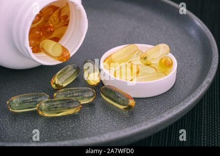 Des capsules d'huile de poisson s'échappant d'une bouteille (Omega 3 supplément). Close up. Banque D'Images