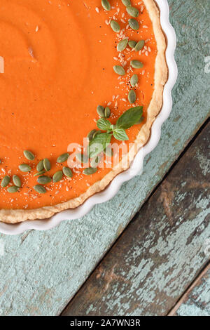 Tarte à la citrouille traditionnelle décorée de citrouille, le lin et les graines d'amarante dans le plat de cuisson sur fond bleu Vue de dessus de l'espace de copie. La récolte ou de l'action de grâce Banque D'Images