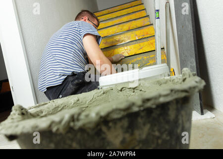 Homme à construire un escalier intérieur et couverte de carreaux en pierre naturelle Banque D'Images