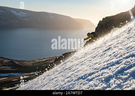 Un homme le ski nordique à l'océan au coucher du soleil en Islande. Banque D'Images