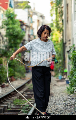 Hanoi, Vietnam - 18 octobre 2019 : une femme vivant sur la célèbre rue de train à Hanoi, Vietnam les eaux et les plantes de son jardin Banque D'Images