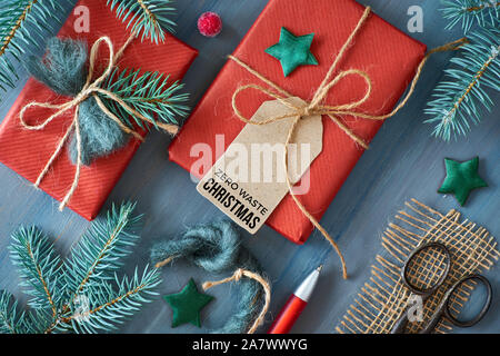 Fond en bois rustique avec des branches de sapin et des cadeaux de Noël cadeau enveloppé dans du papier rouge. Des idées de décorations écologiques. Mise à plat, vue du dessus, t Banque D'Images