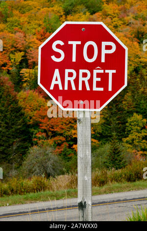 Une image verticale d'un panneau d'arrêt bilingue rouge sur une route au Nouveau-Brunswick au Canada. Banque D'Images