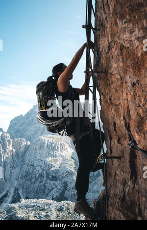 Fille monte une via ferrata lettre sur un mur massif à l'Toblinger Knoten dans les Dolomites, Italie Banque D'Images