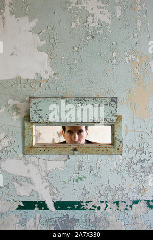 Portrait of a young woman à travers un trou dans un mur d'un bâtiment abandonné. Banque D'Images