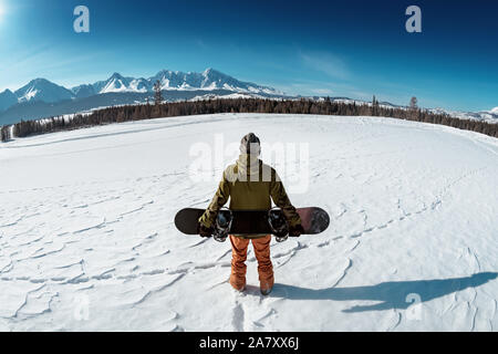 Snowboarder avec snowboard contre les montagnes. Concept de l'arrière-pays Banque D'Images