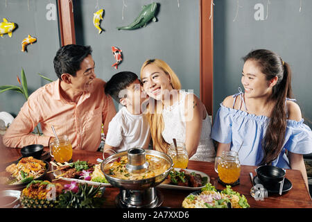 Petit garçon embrassant sa mère sur la joue pendant le dîner en famille dans un restaurant de cuisine asiatique Banque D'Images