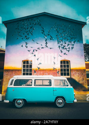 Port Adelaide, Australie - 10 mars 2019 : Classique Volkswagen camper van stationné sur une rue près de l'écriture graffiti wall Banque D'Images