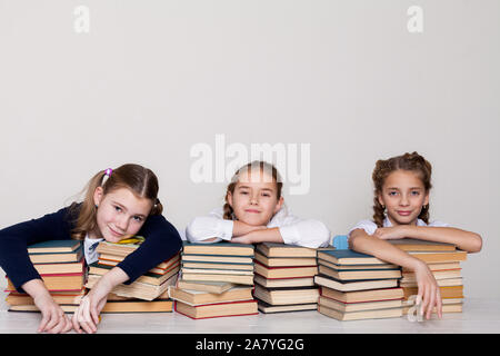 Trois filles d'écolière avec des livres dans la bibliothèque de la classe à la réception Banque D'Images