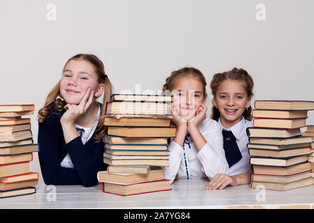 Trois filles d'écolière avec des livres dans la bibliothèque de la classe à la réception Banque D'Images