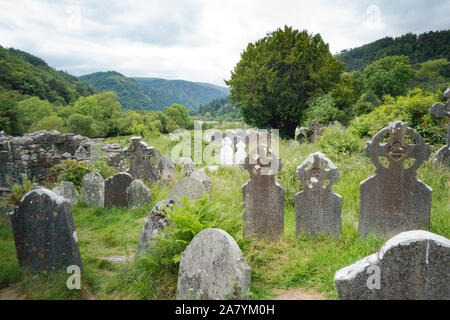 Des pierres tombales dans un cimetière envahi à Glendalough, dans le comté de Wicklow, Irlande Banque D'Images