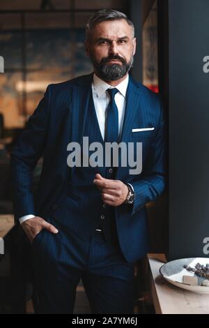 Homme barbu élégant dans un costume standing in modern office Banque D'Images