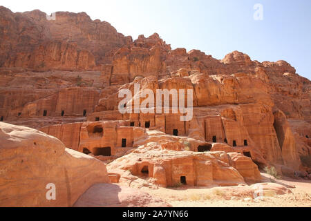 Façades de la rue, qui est, avec les portes des grottes creusées dans la pierre rouge, Petra, Jordanie. Banque D'Images