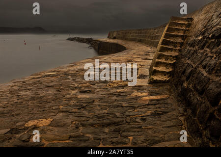 Lyme Regis Dorset Angleterre aube à la Cobb, le mur du port historique de Lyme Regis, durant une tempête, un temps pluvieux Banque D'Images