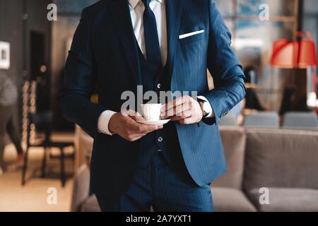 Homme confiant dans smart casual wear holding Coffee cup à son lieu de travail à l'office de tourisme Banque D'Images