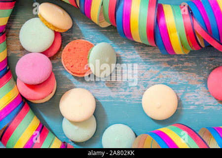 Macarons ou des biscuits avec du papier coloré streamer sur fond bleu, ou d'anniversaire thème carnaval Banque D'Images