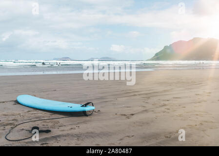 Surf sur sable contre l'océan et le ciel à Playa de Famara, Lanzarote Banque D'Images