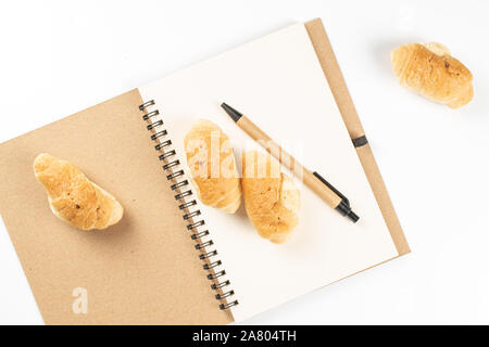 Groupe de quatre entiers et frais cuit mini croissants sur portable avec flatlay stylo isolé sur fond blanc Banque D'Images