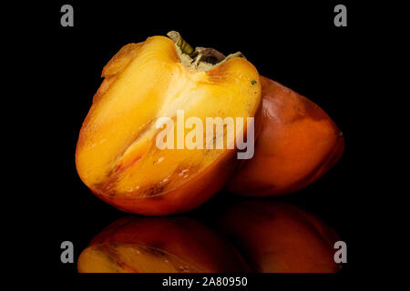 Groupe de deux moitiés de sweet orange Persimmon isolé sur verre noir Banque D'Images