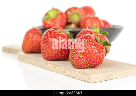 Beaucoup de rouge frais entier de la fraise au bol émaillés sur planche à découper en bois isolé sur fond blanc Banque D'Images