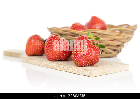 Beaucoup d'entiers et frais, sur la fraise rouge planche à découper en bois rond en rotin bol isolé sur fond blanc Banque D'Images