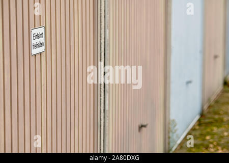 Rangée de portes de garage avec un signe sur la première porte qui dit ' Einfahrt freihalten ' (en anglais : Tenir à l'entrée Effacer ). Vu en Allemagne en novembre. Banque D'Images