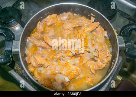 La viande avec les oignons et les carottes à l'étuvée dans une casserole. La cuisine maison Banque D'Images