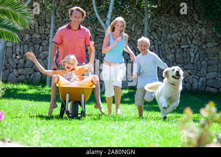 Jeu de la famille dans le jardin avec leur brouette Banque D'Images