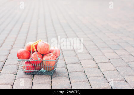 Panier plein de belles pommes juteuses mûres sur le chemin dans le jardin Banque D'Images