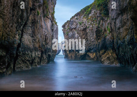 Plage cachée dans Cantabian côte. Castro de las Gaviotas, Asturias. Petite plage dans une falaise tunnel. Playa de la Huelga. Banque D'Images